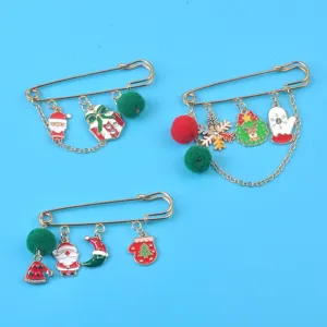 Nahaufnahme von drei weihnachtlichen Broschen mit Weihnachtsmann, Schneeflocke und Bommeln
