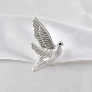 Detailed close-up of a stylish silver-toned peace dove brooch featuring a black gem eye