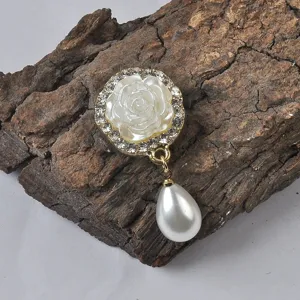 Gedetailleerd zicht op elegante witte roos magnetische broche met druppelparel en strass