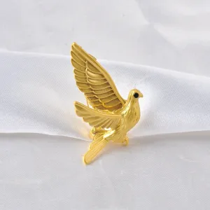 Close-up of elegant gold-toned dove brooch with detailed feather texture on silk.