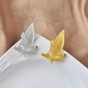 Detailed view of elegant gold and silver peace dove brooches with matte metal finish