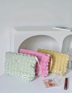 Trousse de maquillage nuage bouffante avec texture plissée douce en vert pastel, rose et jaune.