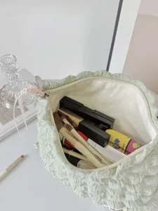 Gros plan sur l'intérieur de la trousse de maquillage bouffante vert clair avec des pinceaux.