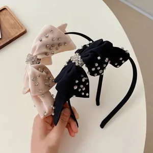 Elegantes diademas con lazos de pedrería brillante en rosa y negro sobre una mesa clara.