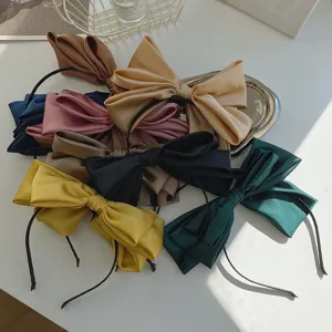 Macro view of multi-colored oversized satin bow headbands with silky texture.