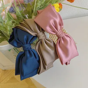 Collection of three large satin bow headbands in pink, champagne, and navy blue