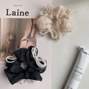 Macro view of elegant organza scrunchies with intricate pearl bow accents