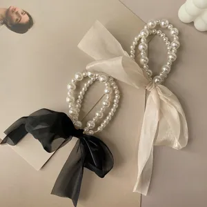 Elegant pearl hair ties featuring sheer organza ribbon bows in black and cream colors.