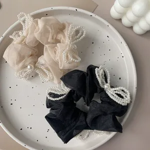 Detail view of elegant organza scrunchies with handcrafted pearl bow accents.