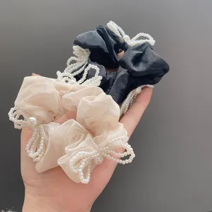 Detailed macro view of elegant fabric scrunchies featuring intricate white pearl bow accents