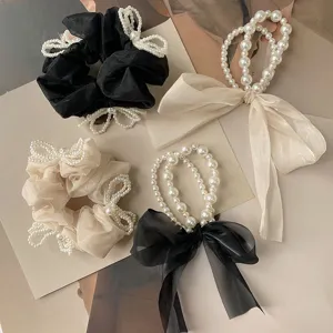 Detail view of pearl bow scrunchies and sheer ribbon hair ties in black and beige