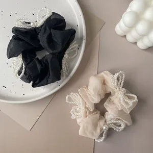 Detail view showing elegant sheer fabric scrunchies decorated with white faux pearl bows.