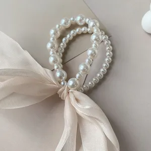 Detailed view of elegant pearl hair tie with large beige organza bow ribbon decoration