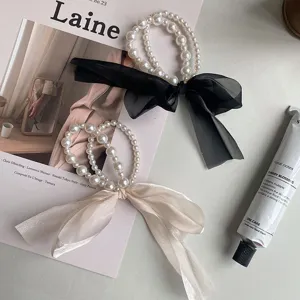Elegant pearl bow hair ties featuring delicate organza ribbons in black and cream.