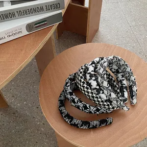 Gros plan de serre-têtes en tricot à motifs pied-de-poule empilés sur une table.