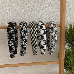 Cinq serre-têtes variés en tricot pied-de-poule et à carreaux sur un support en bois.