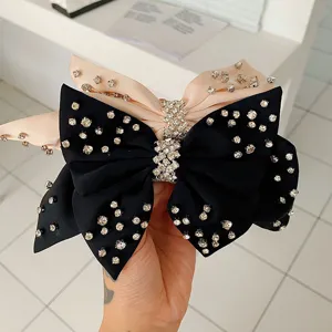 Detalle de elegantes diademas con lazos de satén y pedrería brillante en negro y rosa