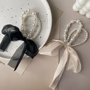 Detail view of elegant Korean pearl bow hair ties with black and beige ribbons.