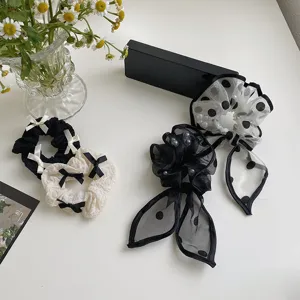Detail shot of black and white bow scrunchies with polka dots and pearls in elegant setting