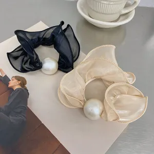 Close-up of elegant organza scrunchies with large pearl decoration in black and beige