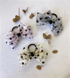 Detail showing three polka dot organza bow hair ties in pink, grey, and cream colors