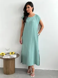 Mint green sleeveless midi dress detail showcasing side slits and textured fabric.