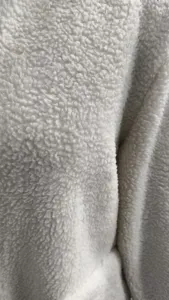 White sherpa fleece fabric detail close up, soft texture and cozy winter apparel material.