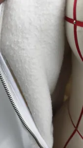 White fleece jumpsuit detail view showcasing soft plush fabric and sturdy white zipper.