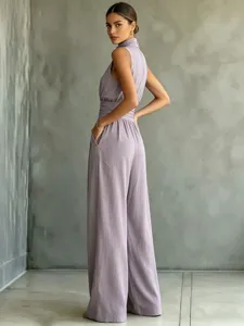 Detailed shot of the sleeveless high-neck wide-leg jumpsuit, highlighting waist pleats.