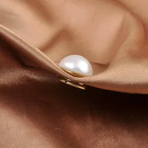 Makroaufnahme einer weißen Perlen-Magnetschnalle auf elegantem braunem Satinstoff.