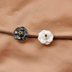 Close-up of black and white camellia flower magnetic brooch pins on silk fabric