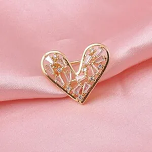 Dettaglio di una spilla magnetica a forma di cuore con cristalli lucenti su seta rosa.