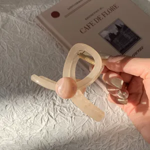 Gros plan d'une pince à cheveux crème avec une perle décorative marbrée rose