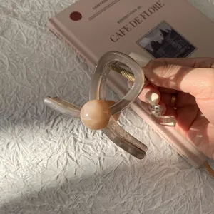 Pince à cheveux élégante en résine brune avec une perle de marbre décorative en main