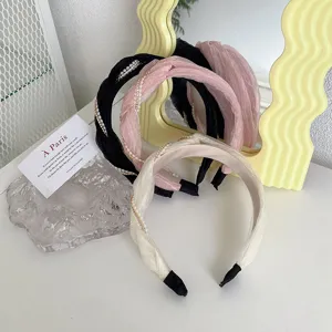 Primo piano di cerchietti in tessuto arricciato con perle in nero, rosa e crema