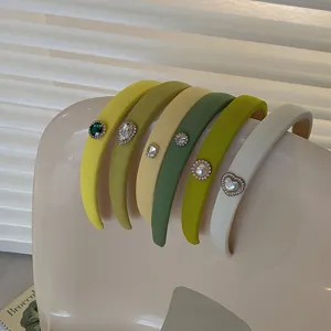 Close-up of green padded headbands with rhinestone heart and pearl embellishments