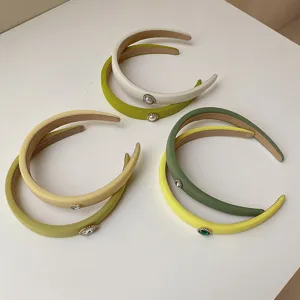 Macro detail of green and yellow padded headbands with rhinestone heart embellishments.