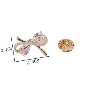 Elegante goudkleurige strikbroche met zirkonia en afmetingen van 2,4cm x 2,1cm