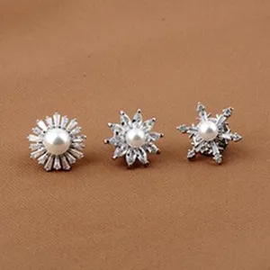 Dettaglio di spille a fiore e fiocco di neve in argento con perle e cristalli.