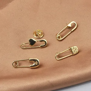 Detailaufnahme eleganter goldener Sicherheitsnadel-Broschen mit Herz und Stern auf Seide.