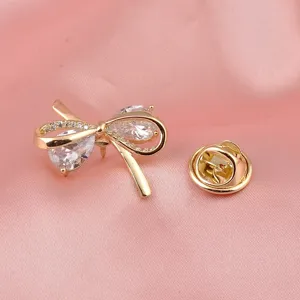 Gedetailleerd overzicht van een elegante gouden strikbroche met heldere zirkonia-stenen