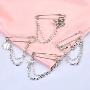 Detailed view of silver hip-hop safety pin brooches with butterfly and cross charms