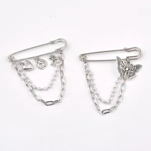 Detail of silver safety pin brooches with butterfly, heart charms and layered chains.