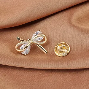 Detailopname van een elegante gouden strikbrosche met sprankelende zirkonia-stenen