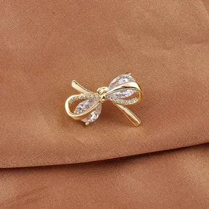 Close-up van een elegante strikbroche met peervormige heldere zirkonia in goudkleur