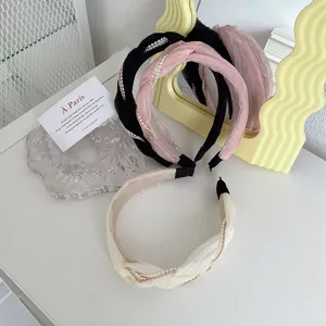 Primo piano di eleganti cerchietti a pieghe intrecciati con accenti di catena di perle.