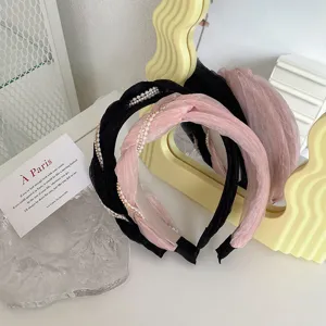 Primo piano di cerchietti in tessuto plissettato ritorto con perle in nero e rosa