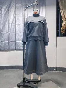 Grey knit two-piece set, high neck top with pockets and long skirt, detailed studio view.