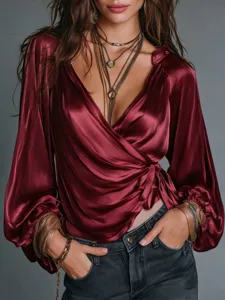 Close-up detail of women's burgundy satin wrap V-neck long sleeve blouse paired with stylish jeans.