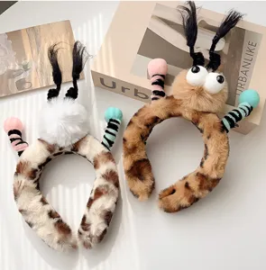 Gros plan de serre-têtes en peluche léopard avec de grands yeux et des tresses.